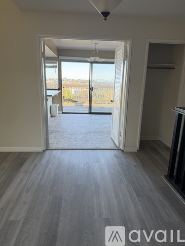 A room with a view of a fence and trees through a sliding glass door.