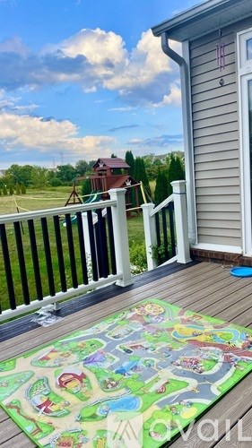 A play mat on a deck with a house and trees in the background.