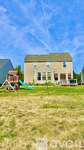 A house with a green lawn and a playground in front.