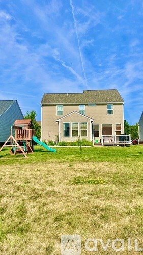 A house with a green lawn and a playground in front.