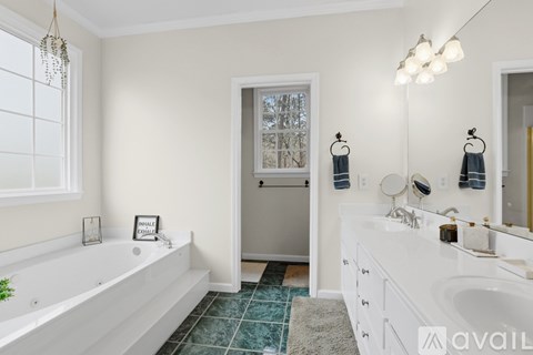 A bathroom with a white tub, sink, and towel racks.
