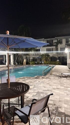 A poolside table with chairs and an umbrella over it.