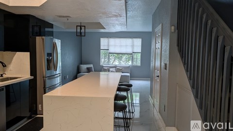 A kitchen with a white island and black cabinets.