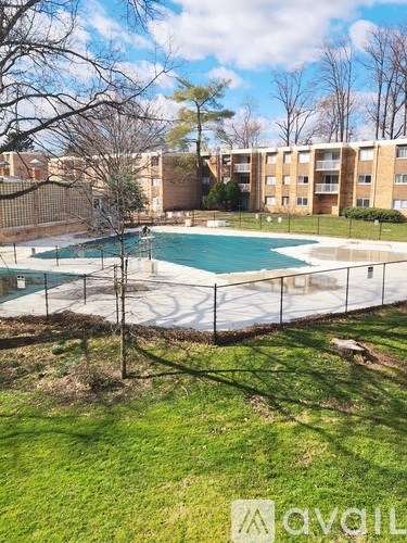 A pool surrounded by a fence and apartment buildings.