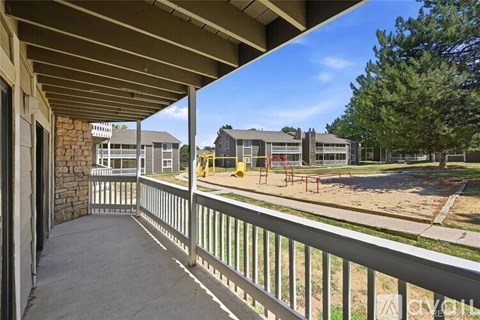 A view from a covered walkway looking out to a playground and houses.