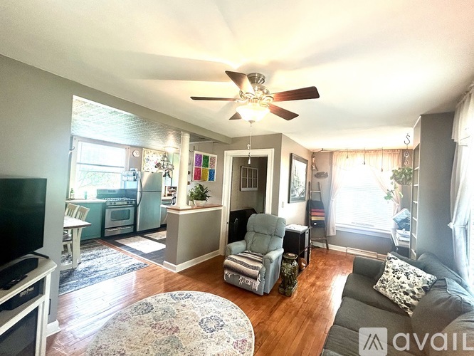 A living room with a television, a couch, and a rug.