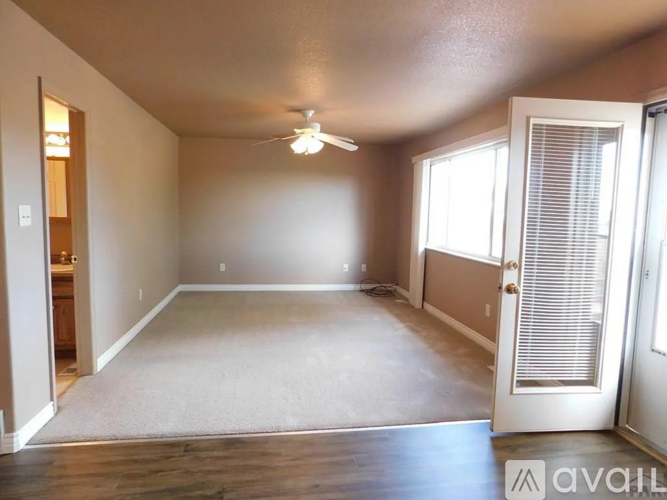 A spacious room with a ceiling fan and a carpeted floor.