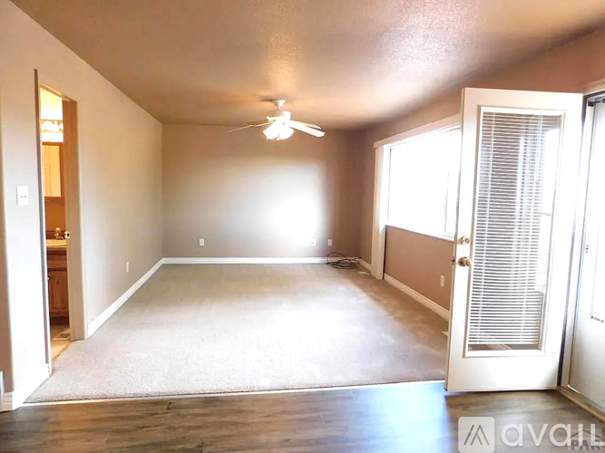 A spacious room with a ceiling fan and a door on the right side.