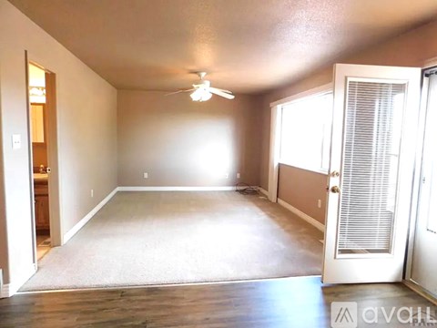 A spacious room with a ceiling fan and a door on the right side.
