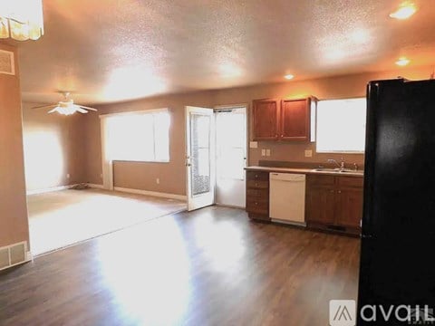 A kitchen with a black refrigerator and wooden cabinets.