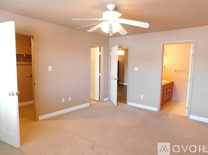 A spacious room with a ceiling fan and four doors.