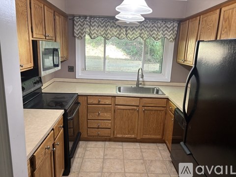 A kitchen with wooden cabinets and a window with a chevron patterned valance.