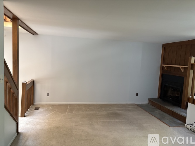 A spacious living room with a fireplace and a carpeted floor.