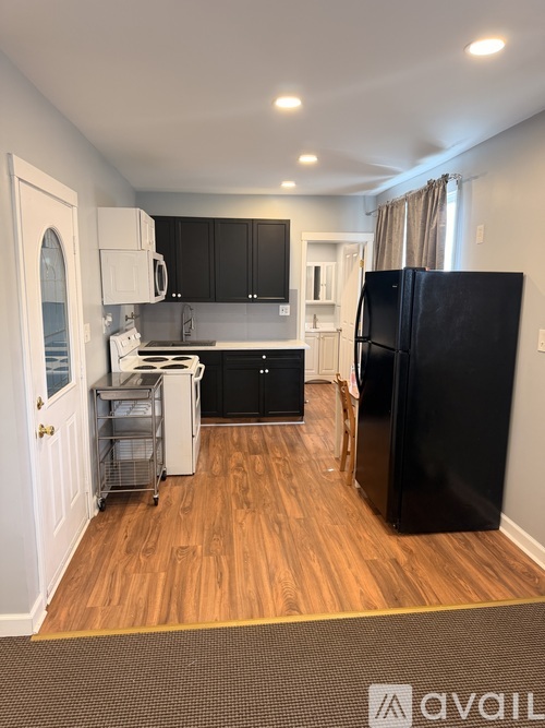 A kitchen with a black fridge and wooden floors.