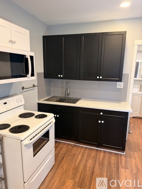 A kitchen with black cabinets and a white stove top oven.