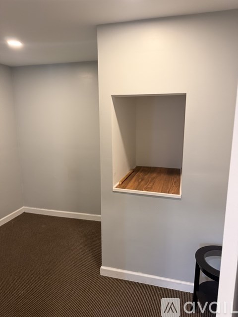 A small closet with a shelf and a trash can.