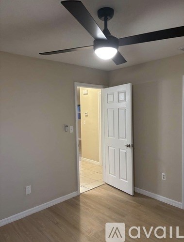 A room with a ceiling fan and a door.