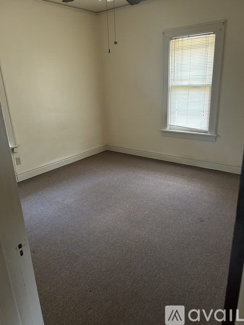 A room with a carpeted floor and a window with blinds.