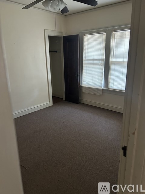 A room with a carpeted floor and a ceiling fan.