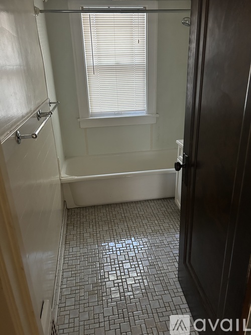 A bathroom with a black door and a window with blinds.