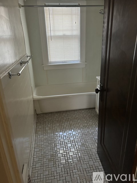 A bathroom with a black door and a window with blinds.