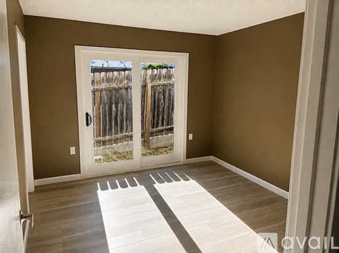 A room with a sliding door leading to a backyard.