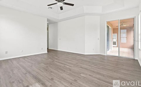 A spacious room with a ceiling fan and sliding glass doors.