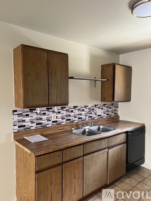 A kitchen with wooden cabinets and a black dishwasher.