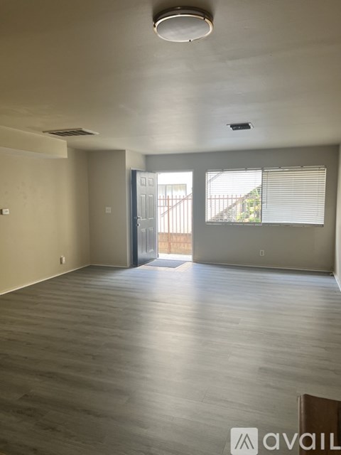 A spacious room with wooden flooring and a sliding glass door leading outside.