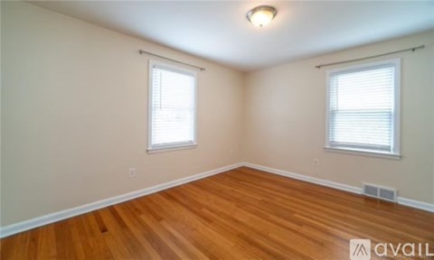 A room with wooden floors and two windows.