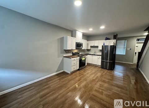 A kitchen with white cabinets and a wooden floor.