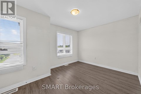 A room with a window and a wooden floor.