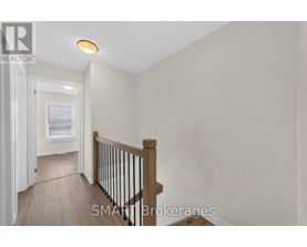 A hallway with a wooden floor and a white door leading to another room.