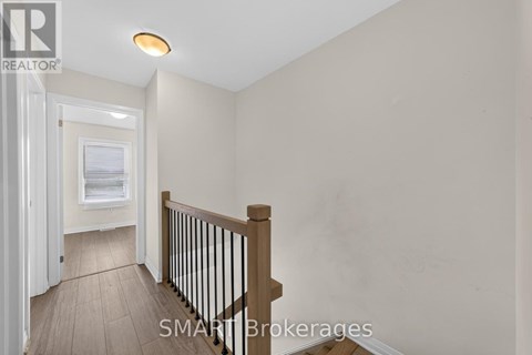 A hallway with a wooden floor and a white door leading to another room.