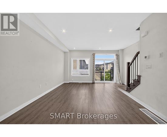 A spacious room with wooden flooring and a view of a cityscape through the window.