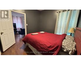 A bedroom with a red bedspread and a white door.