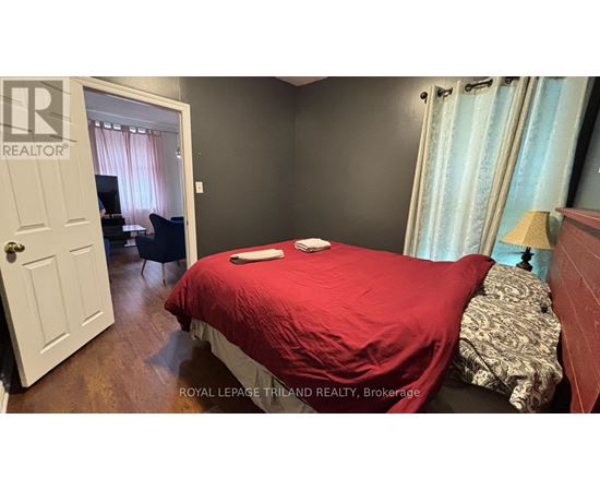 A bedroom with a red bedspread and a white door.