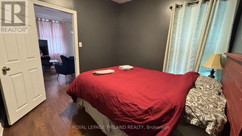 A bedroom with a red bedspread and a white door.