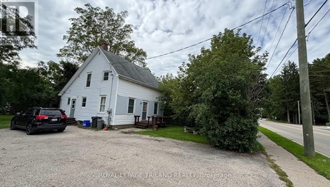 A white house with a gravel driveway in front.
