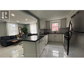 A well-lit kitchen with a black countertop and stainless steel appliances.
