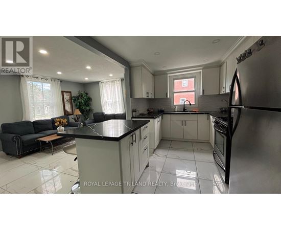 A well-lit kitchen with a black countertop and stainless steel appliances.