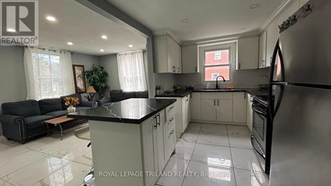 A well-lit kitchen with a black countertop and stainless steel appliances.