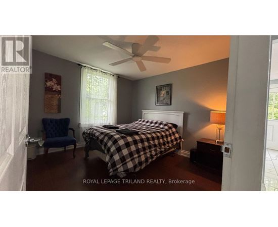 A bedroom with a bed, chair, and a ceiling fan.