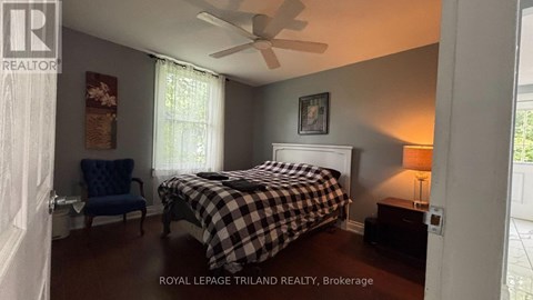 A bedroom with a bed, chair, and a ceiling fan.