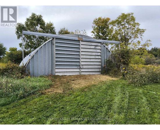 A large metal shed sits in a grassy field.