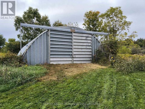 A large metal shed sits in a grassy field.
