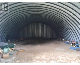 A large, empty, curved tunnel under construction with construction materials scattered around.