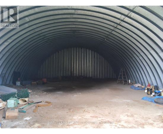 A large, empty, curved tunnel under construction with construction materials scattered around.
