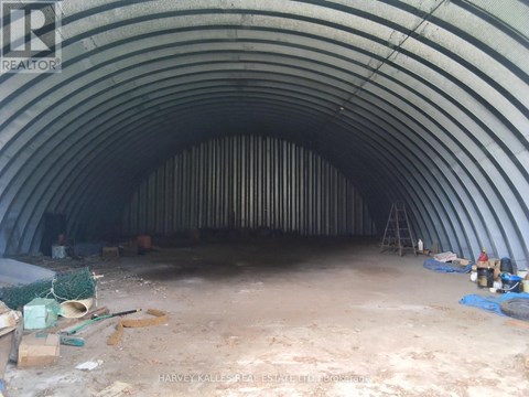 A large, empty, curved tunnel under construction with construction materials scattered around.