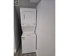 A white dryer is in a small room with a grey wall.